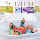 Happy baby playing with hanging crinkle cloth books in a crib